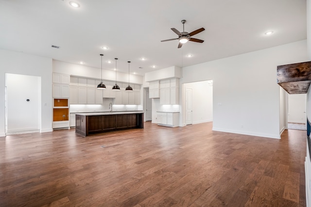 unfurnished living room featuring ceiling fan, sink, and dark wood-type flooring