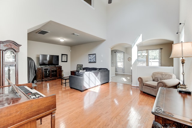 living room featuring a towering ceiling and light hardwood / wood-style flooring