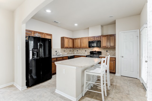 kitchen with backsplash, black appliances, sink, a kitchen island, and a breakfast bar area