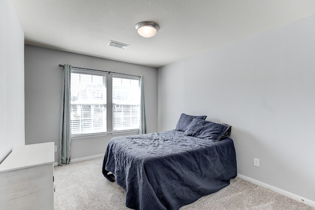 bedroom with light colored carpet and a textured ceiling