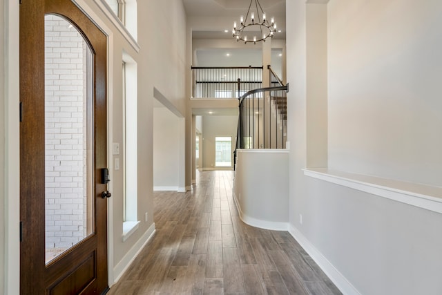 hall featuring hardwood / wood-style floors, a towering ceiling, and a notable chandelier