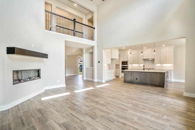 unfurnished living room featuring light hardwood / wood-style flooring and a towering ceiling