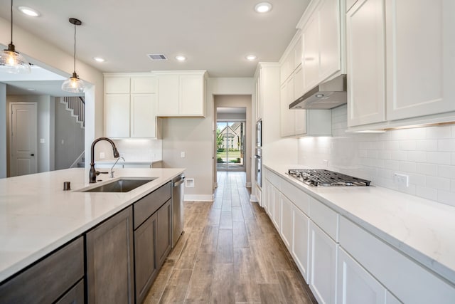 kitchen with stainless steel appliances, sink, pendant lighting, light hardwood / wood-style floors, and white cabinetry