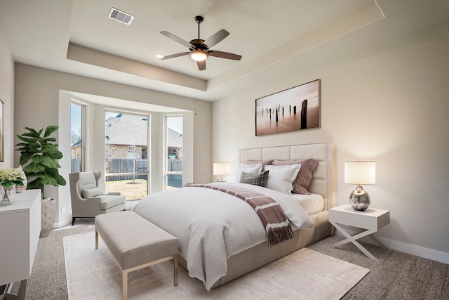 bedroom featuring a raised ceiling, ceiling fan, and light colored carpet