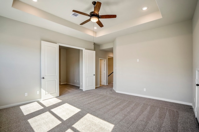 unfurnished bedroom with light carpet, a raised ceiling, and ceiling fan