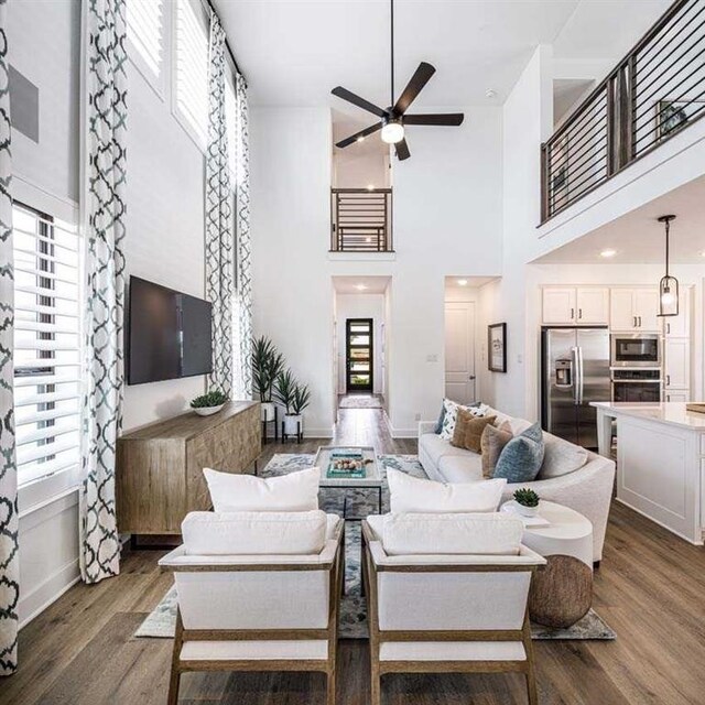 living room featuring a high ceiling, plenty of natural light, and dark wood-type flooring