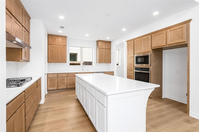 7427 Cattail Falls Ln, Porter, TX 77365 - kitchen with stainless steel appliances, under cabinet range hood, light wood-style floors, backsplash, and recessed lighting