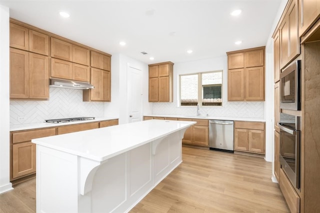 7427 Cattail Falls Ln, Porter, TX 77365 - kitchen featuring appliances with stainless steel finishes, under cabinet range hood, a sink, decorative backsplash, and recessed lighting