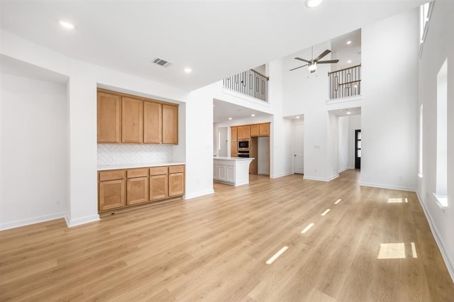7427 Cattail Falls Ln, Porter, TX 77365 - unfurnished living room with a ceiling fan, light wood finished floors, recessed lighting, baseboards, and a towering ceiling