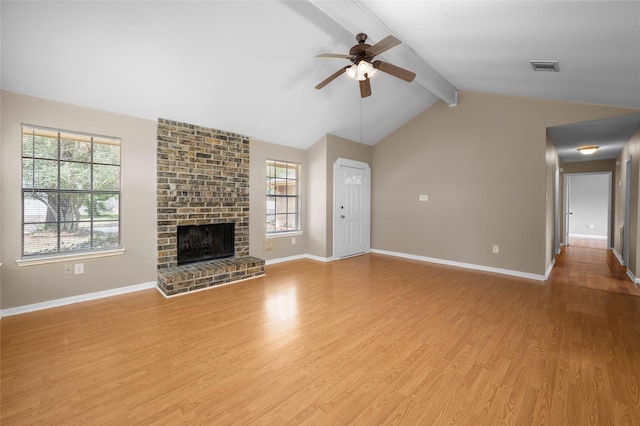 unfurnished living room with lofted ceiling with beams, ceiling fan, a healthy amount of sunlight, and a fireplace