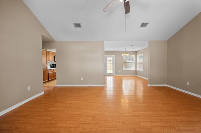 unfurnished living room with ceiling fan with notable chandelier and light hardwood / wood-style flooring