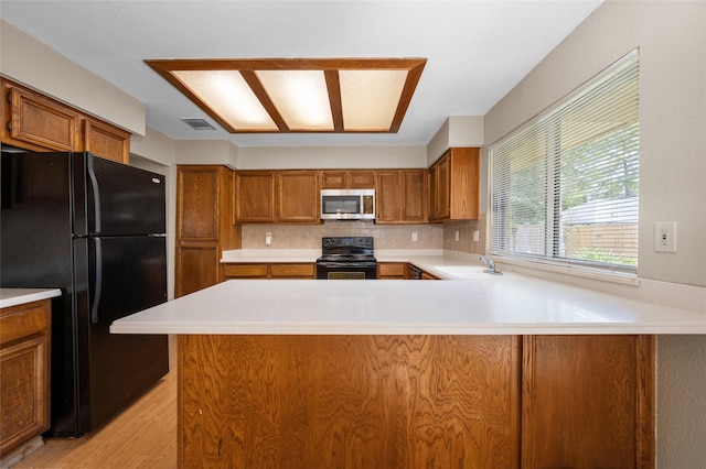 kitchen featuring backsplash, kitchen peninsula, sink, and black appliances