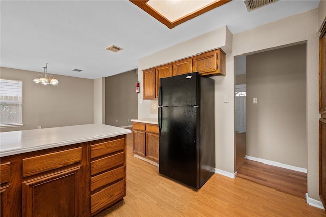 kitchen featuring black refrigerator, pendant lighting, light hardwood / wood-style flooring, and a notable chandelier