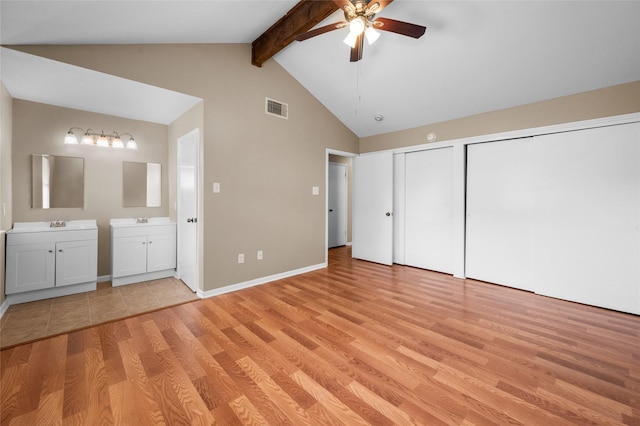 unfurnished bedroom with sink, light hardwood / wood-style flooring, ceiling fan, connected bathroom, and beamed ceiling