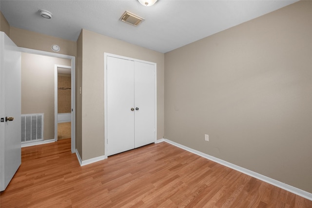 unfurnished bedroom with light wood-type flooring and a closet