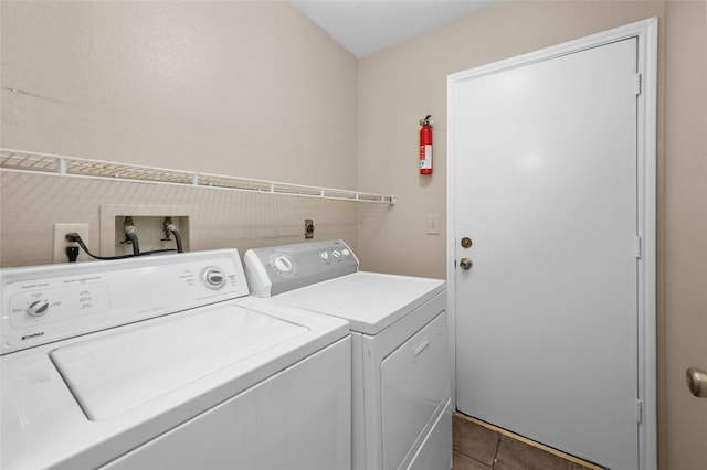 clothes washing area with dark tile patterned floors and independent washer and dryer