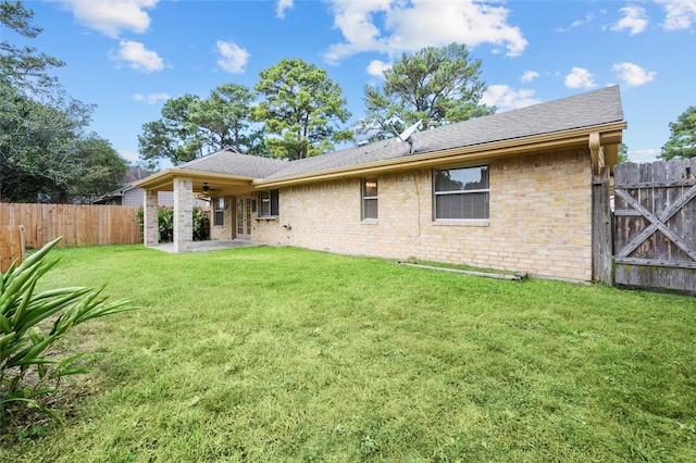 rear view of property featuring ceiling fan, a patio area, and a yard