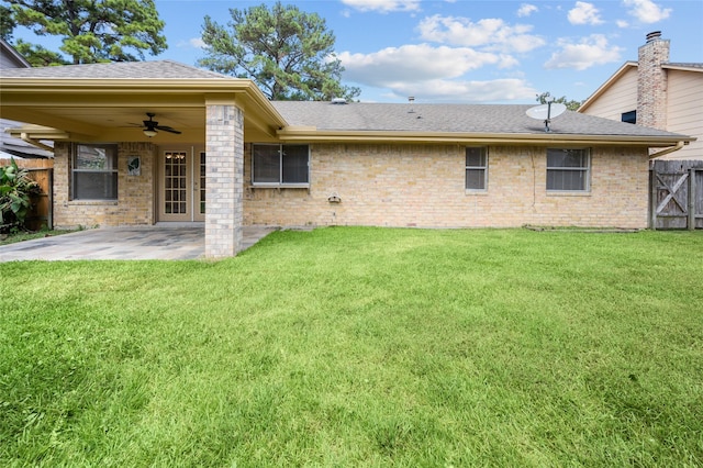 rear view of property featuring ceiling fan, a patio area, and a yard