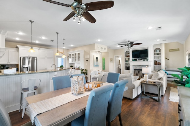 dining space featuring built in shelves, dark hardwood / wood-style floors, ceiling fan, and sink