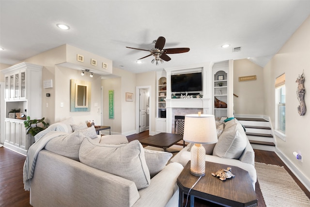 living room featuring built in shelves, ceiling fan, and dark hardwood / wood-style flooring