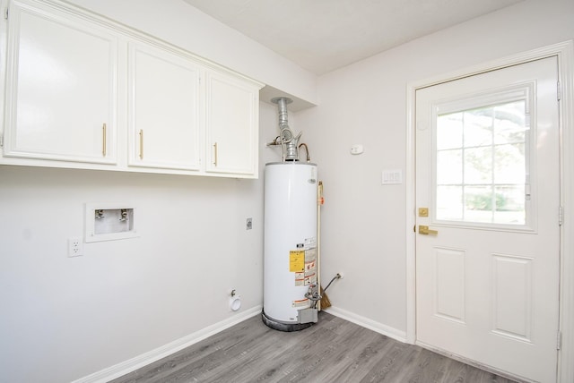 washroom featuring electric dryer hookup, water heater, cabinets, and light wood-type flooring