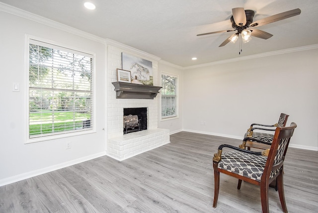 living area featuring wood-type flooring, a brick fireplace, plenty of natural light, and crown molding