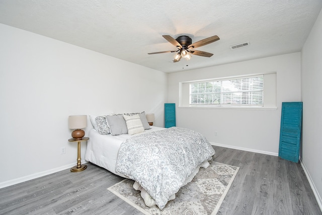 bedroom featuring ceiling fan, wood-type flooring, and a textured ceiling