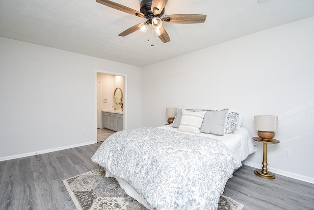 bedroom with ceiling fan, ensuite bathroom, and dark hardwood / wood-style floors