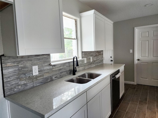 kitchen featuring decorative backsplash, white cabinets, light stone counters, sink, and dishwasher