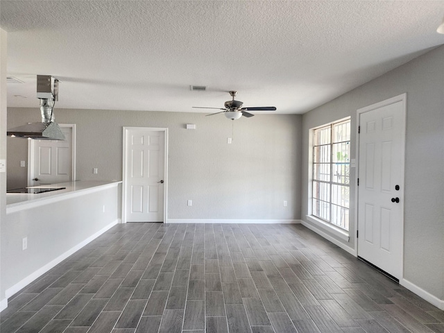 unfurnished living room with a textured ceiling and ceiling fan