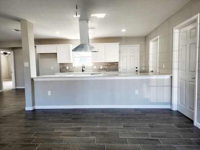 kitchen with white cabinets, sink, kitchen peninsula, and backsplash