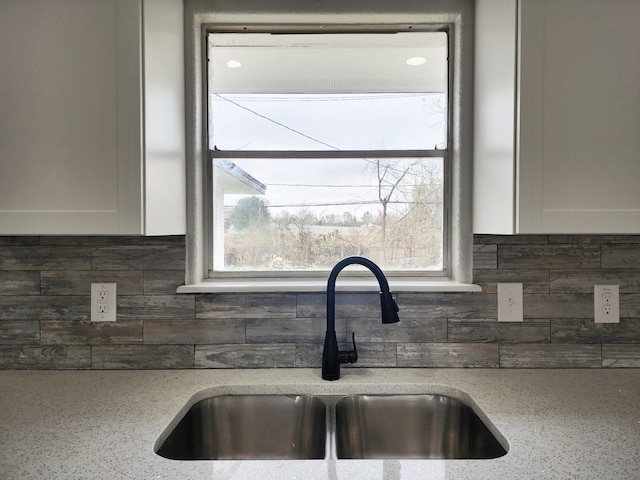 kitchen with tasteful backsplash, sink, white cabinetry, and light stone countertops