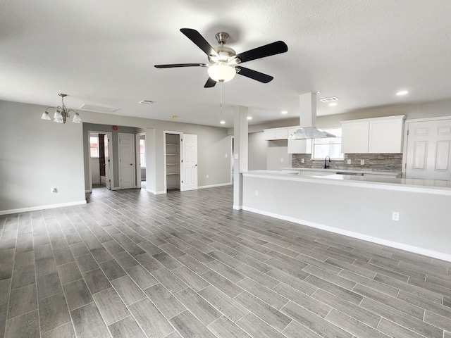 unfurnished living room featuring sink, ceiling fan with notable chandelier, and light hardwood / wood-style flooring