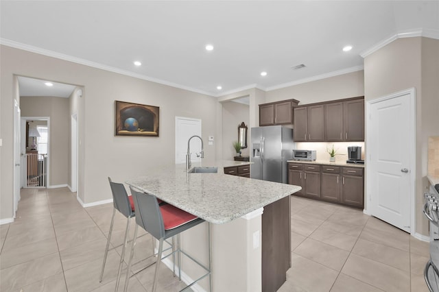 kitchen featuring appliances with stainless steel finishes, an island with sink, sink, a kitchen breakfast bar, and light tile patterned floors