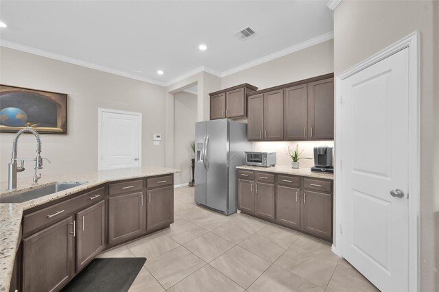 kitchen featuring dark brown cabinetry, light stone countertops, sink, stainless steel refrigerator with ice dispenser, and ornamental molding