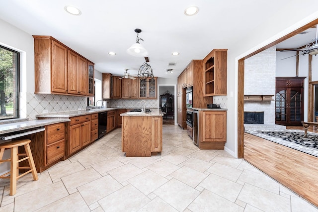 kitchen with light stone counters, a fireplace, pendant lighting, dishwasher, and a kitchen island