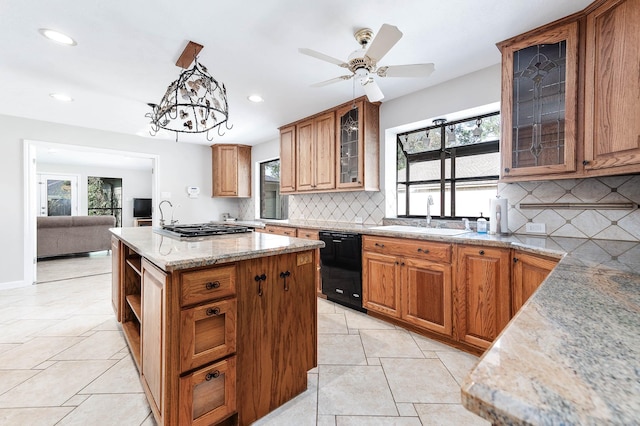 kitchen featuring light stone countertops, a center island, sink, pendant lighting, and black dishwasher