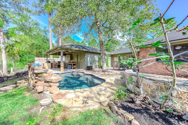 view of swimming pool with exterior bar, a patio, area for grilling, and ceiling fan