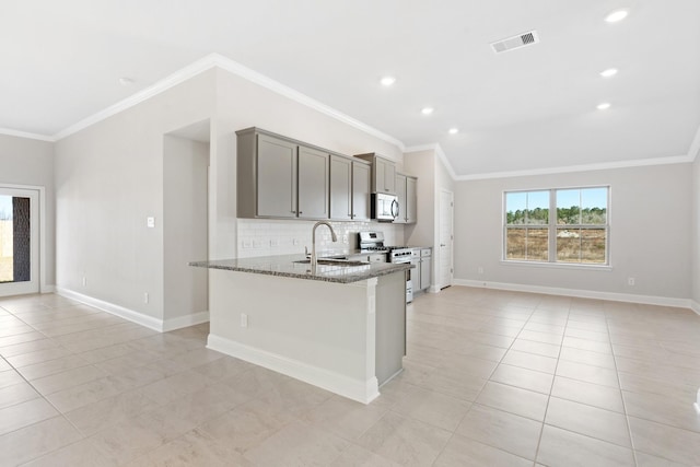 kitchen with gray cabinetry, crown molding, stainless steel appliances, and dark stone counters