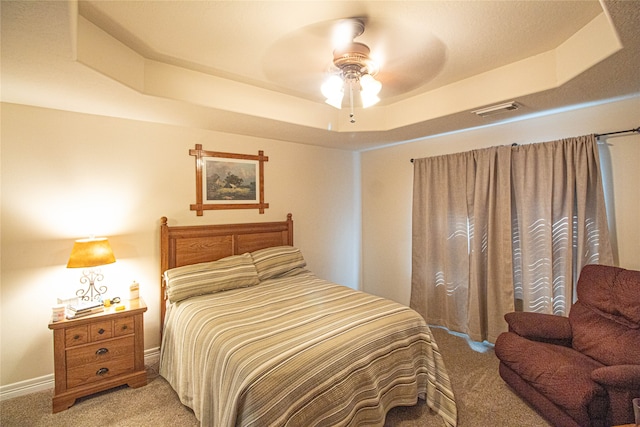 bedroom featuring carpet floors, a raised ceiling, and ceiling fan