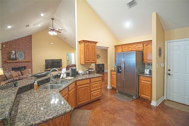 kitchen featuring ceiling fan, sink, high vaulted ceiling, stainless steel fridge, and a fireplace