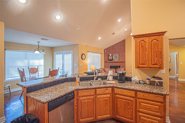 kitchen with a brick fireplace, stainless steel dishwasher, vaulted ceiling, sink, and a chandelier