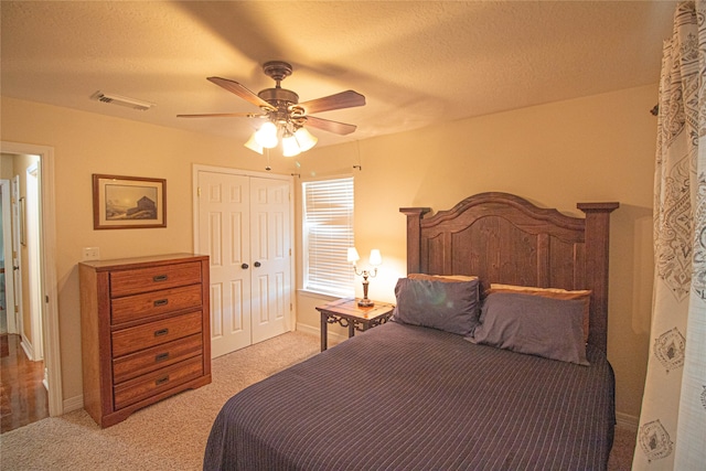 carpeted bedroom featuring ceiling fan, a textured ceiling, and a closet