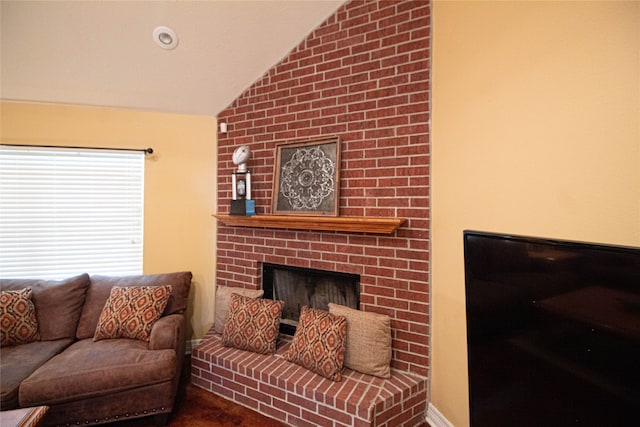 living room featuring a brick fireplace and vaulted ceiling