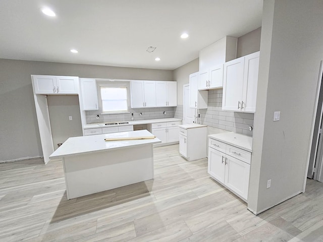 kitchen with tasteful backsplash, white cabinets, light hardwood / wood-style flooring, and a kitchen island