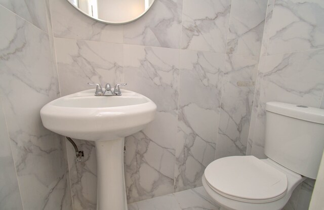 bathroom with toilet and tile walls