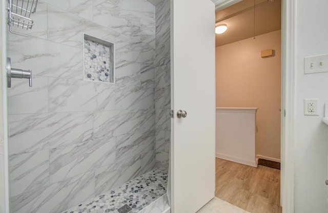 bathroom with hardwood / wood-style floors and tiled shower