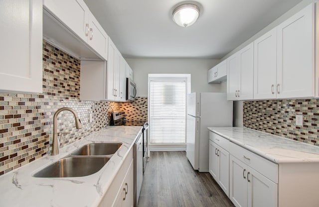 kitchen featuring appliances with stainless steel finishes, tasteful backsplash, sink, hardwood / wood-style floors, and white cabinetry