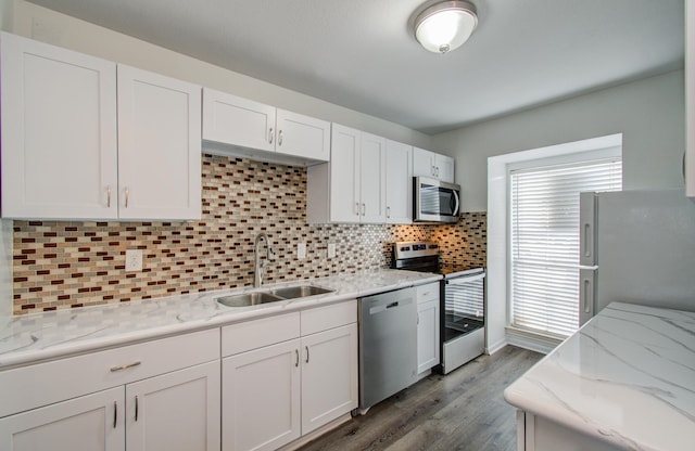 kitchen with appliances with stainless steel finishes, backsplash, sink, wood-type flooring, and white cabinetry