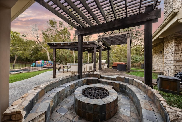 patio terrace at dusk with a fire pit, fence, and a pergola